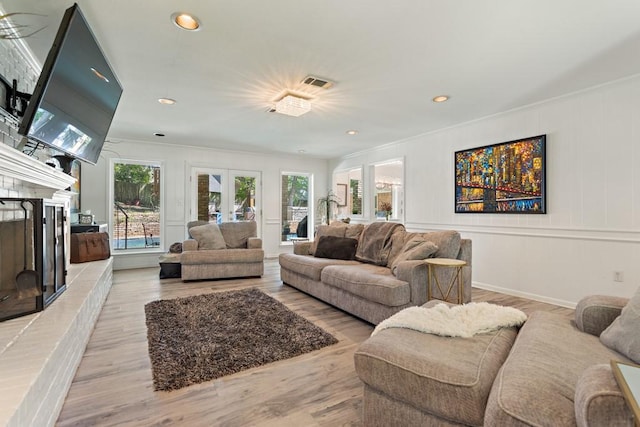 living room featuring light wood-type flooring, ornamental molding, and french doors