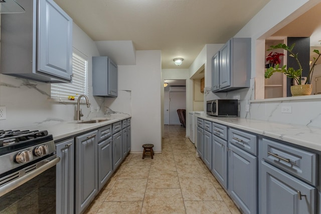 kitchen featuring stainless steel appliances, light stone counters, gray cabinetry, and sink