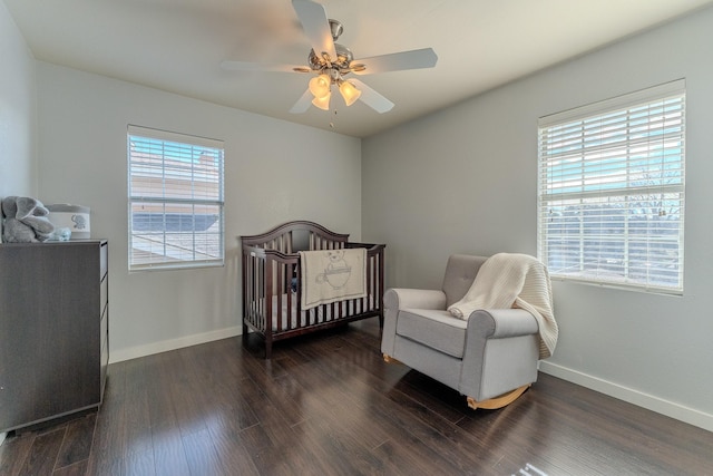 bedroom with ceiling fan, dark wood-type flooring, and a nursery area