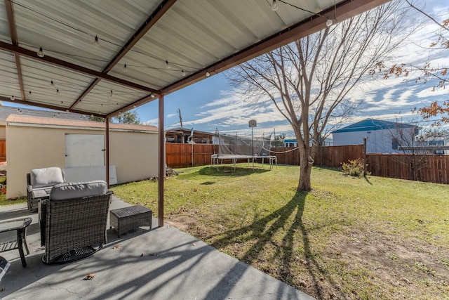 view of yard with a trampoline and a patio