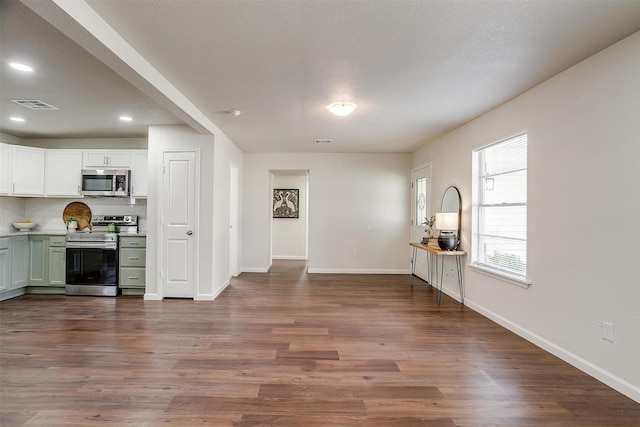 kitchen with backsplash, dark hardwood / wood-style flooring, white cabinets, and stainless steel appliances