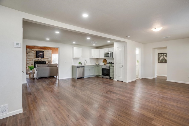 unfurnished living room with dark hardwood / wood-style floors, a stone fireplace, and sink