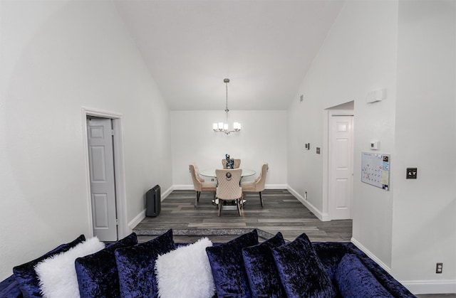 dining area featuring dark wood-type flooring, high vaulted ceiling, and a notable chandelier