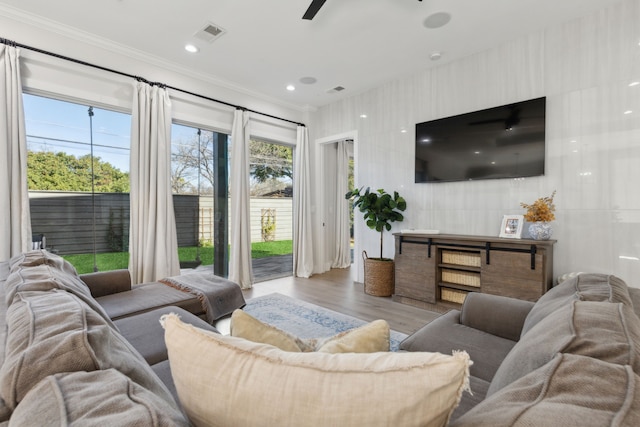 living room featuring light wood-type flooring, ceiling fan, and crown molding