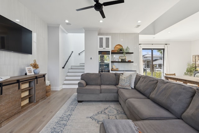 living room featuring ceiling fan, ornamental molding, and light wood-type flooring