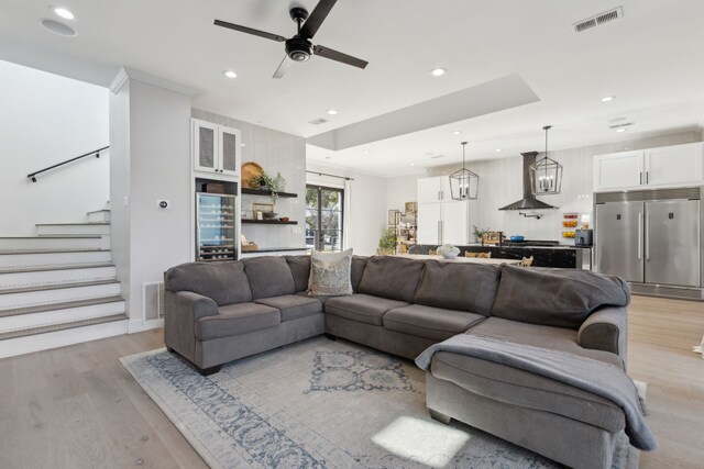 living room with ceiling fan with notable chandelier and light hardwood / wood-style floors