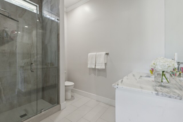 bathroom featuring tile patterned floors, vanity, a shower with door, crown molding, and toilet