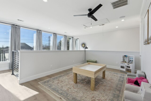 sitting room with ceiling fan, ornamental molding, and light wood-type flooring