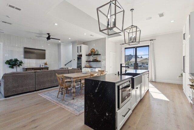 kitchen featuring decorative light fixtures, light wood-type flooring, white cabinetry, and ceiling fan with notable chandelier