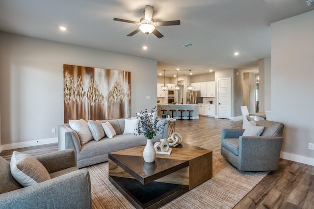 living area with recessed lighting, visible vents, baseboards, and wood finished floors