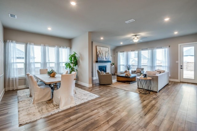 dining room with wood finished floors, visible vents, baseboards, recessed lighting, and a glass covered fireplace