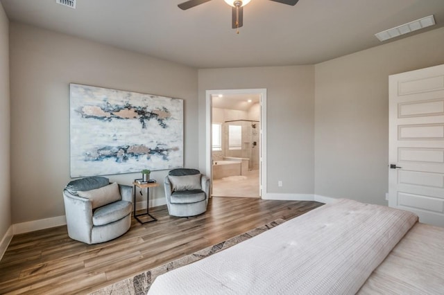 bedroom featuring wood finished floors, visible vents, ensuite bathroom, and baseboards