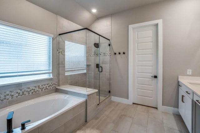 bathroom with a bath, a shower stall, vanity, and baseboards