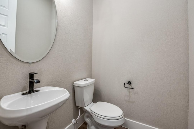 bathroom with a sink, toilet, and a textured wall