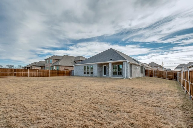 rear view of property with a yard, a fenced backyard, and brick siding