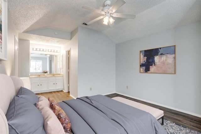 bedroom featuring vaulted ceiling, a textured ceiling, and light wood-type flooring