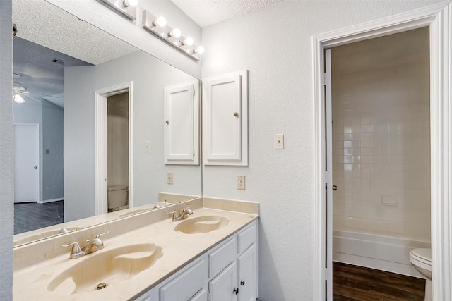 full bathroom featuring vanity, hardwood / wood-style floors, a textured ceiling, and toilet