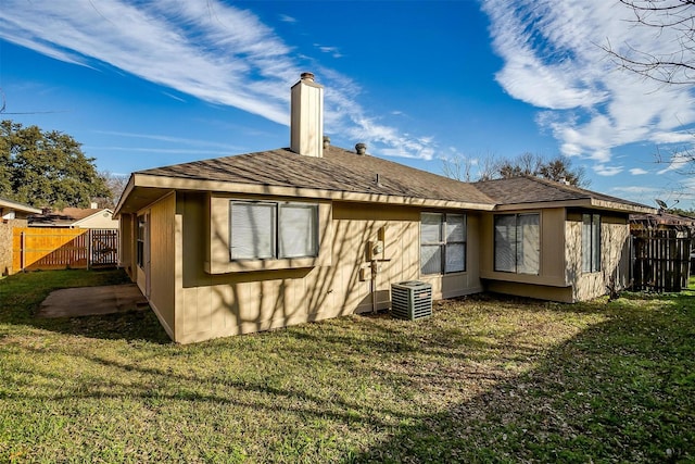 rear view of house featuring cooling unit and a yard