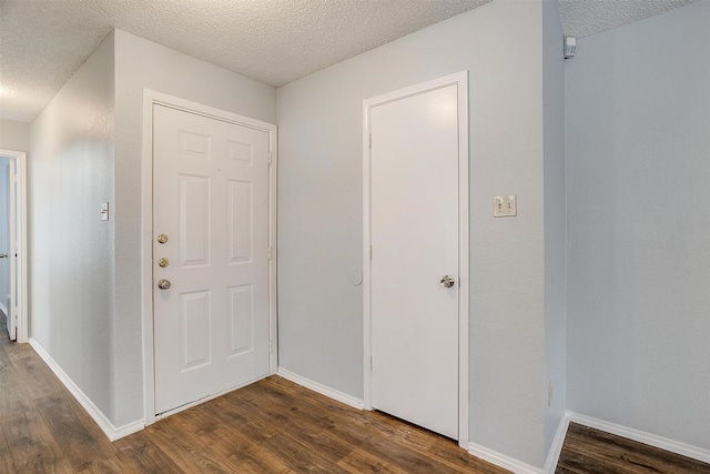 foyer featuring a textured ceiling and dark wood-type flooring