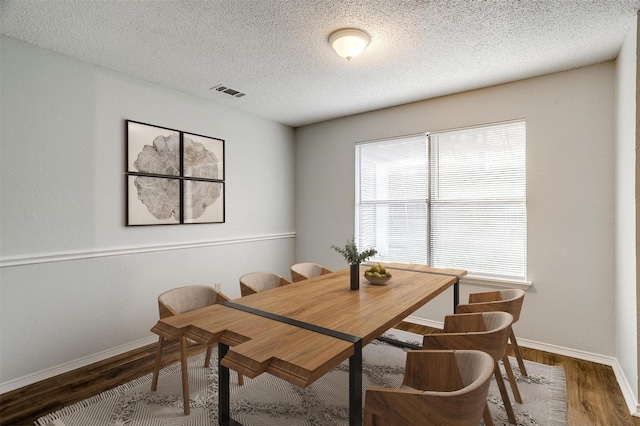 dining room featuring a textured ceiling and dark hardwood / wood-style floors