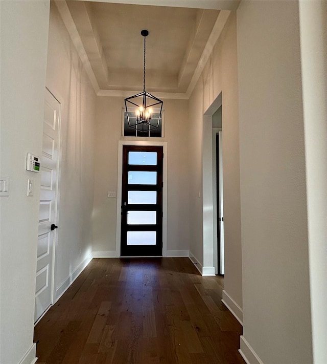 foyer featuring a chandelier, a raised ceiling, and dark wood-type flooring