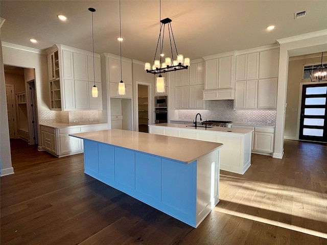 kitchen featuring a kitchen island with sink, white cabinets, and an inviting chandelier