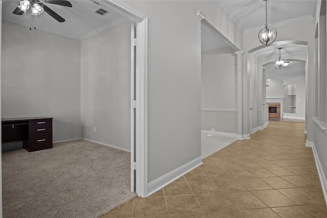 hallway featuring ornate columns, a chandelier, light tile patterned floors, and crown molding