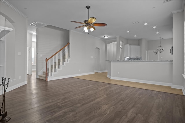 unfurnished living room featuring ceiling fan with notable chandelier, crown molding, and dark hardwood / wood-style floors