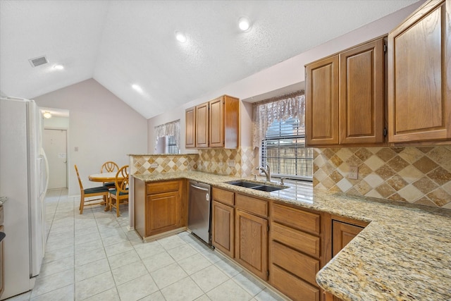 kitchen with lofted ceiling, white refrigerator, sink, stainless steel dishwasher, and light stone countertops