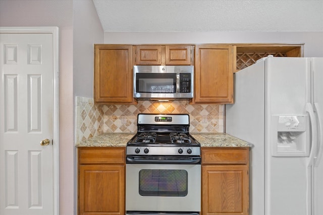 kitchen featuring backsplash, light stone countertops, and appliances with stainless steel finishes