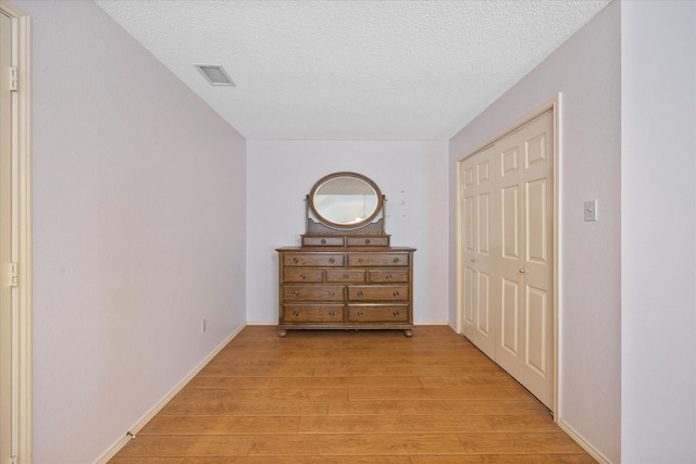 hall featuring a textured ceiling and light hardwood / wood-style floors