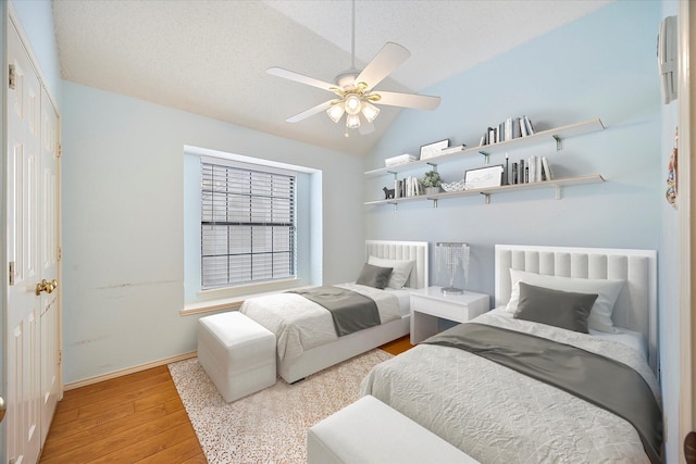 bedroom with a textured ceiling, light wood-type flooring, ceiling fan, and lofted ceiling