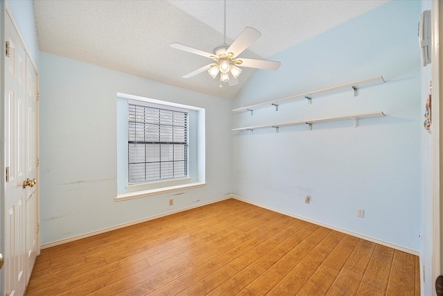 spare room featuring a textured ceiling, light hardwood / wood-style floors, vaulted ceiling, and ceiling fan