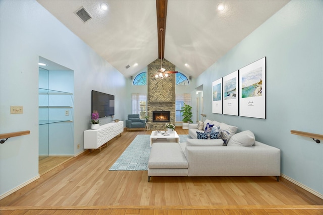 living room with hardwood / wood-style floors, beam ceiling, a stone fireplace, and high vaulted ceiling