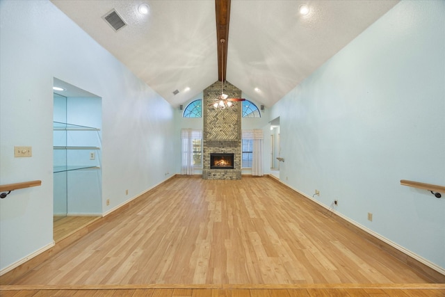 unfurnished living room featuring beam ceiling, light hardwood / wood-style floors, a fireplace, and high vaulted ceiling