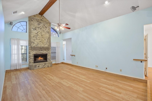 unfurnished living room with a fireplace, beam ceiling, light wood-type flooring, and plenty of natural light