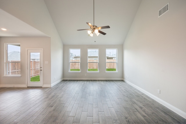 empty room featuring wood-type flooring, high vaulted ceiling, and ceiling fan