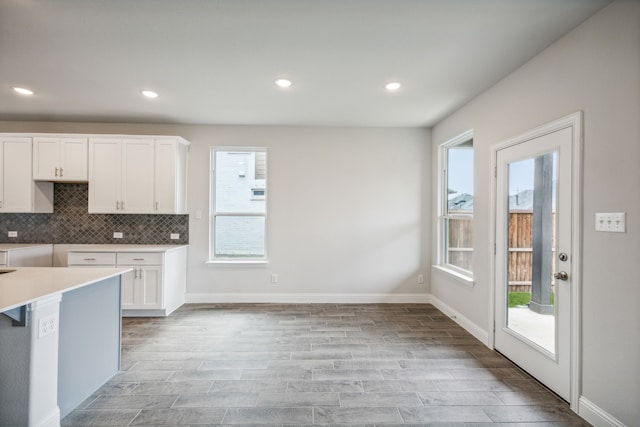 kitchen with tasteful backsplash, white cabinets, and light wood-type flooring