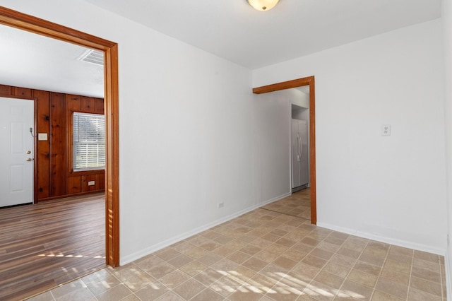 unfurnished room featuring wooden walls