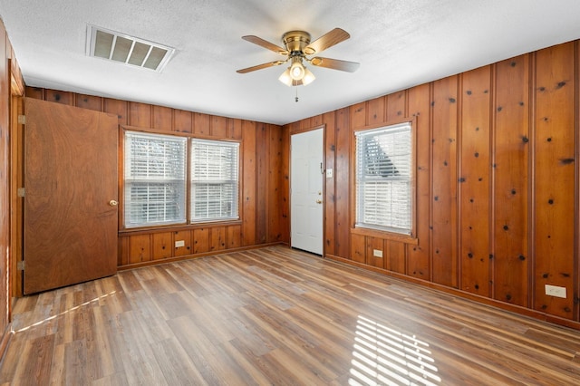 unfurnished room featuring hardwood / wood-style flooring, ceiling fan, a textured ceiling, and a wealth of natural light