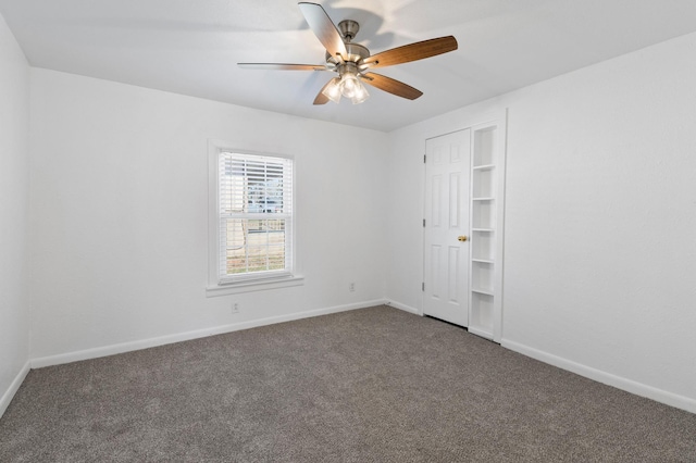 spare room featuring dark carpet and ceiling fan