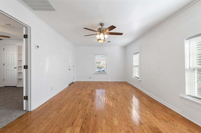 spare room with light wood-type flooring, ceiling fan, and a healthy amount of sunlight