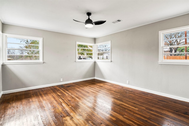 empty room with dark hardwood / wood-style floors, a healthy amount of sunlight, and ceiling fan