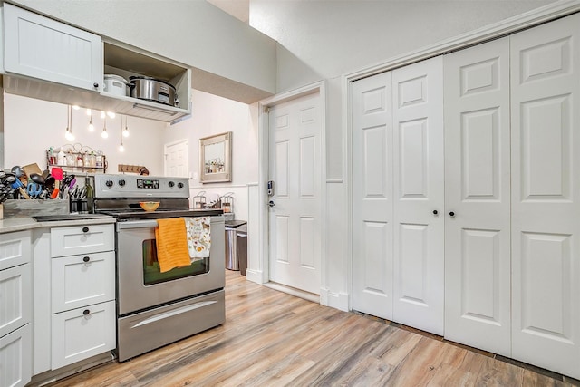 kitchen with stainless steel electric stove, white cabinets, and light hardwood / wood-style flooring