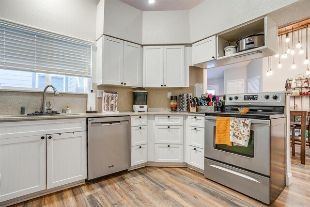 kitchen with tasteful backsplash, stainless steel appliances, sink, light hardwood / wood-style flooring, and white cabinets