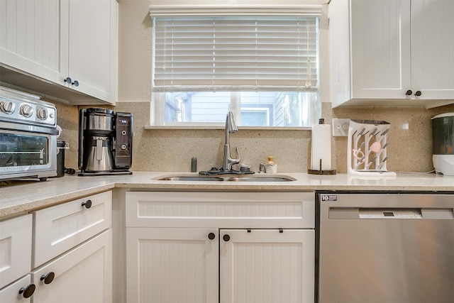 kitchen with dishwasher, tasteful backsplash, white cabinetry, and sink