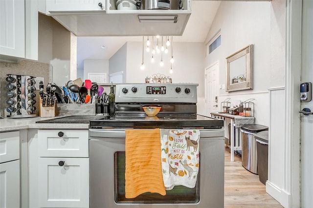 kitchen featuring electric range, white cabinetry, hanging light fixtures, and light hardwood / wood-style flooring