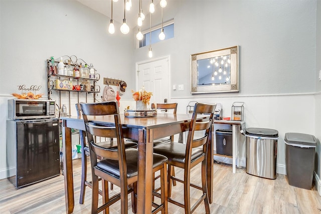 dining space with a high ceiling and light wood-type flooring