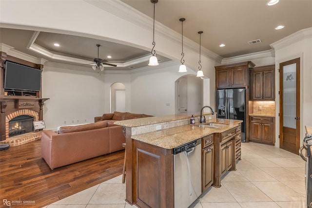 kitchen with appliances with stainless steel finishes, pendant lighting, sink, a kitchen island with sink, and a raised ceiling