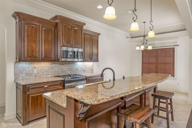 kitchen featuring appliances with stainless steel finishes, decorative light fixtures, sink, decorative backsplash, and a center island with sink